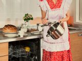 Housewife loads the dishes in the dishwasher. 1950s style post processing emulation.