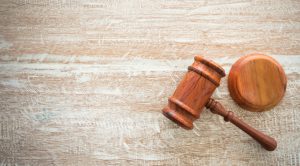 wooden judges gavel and soundboard resting on top of wooden desk.